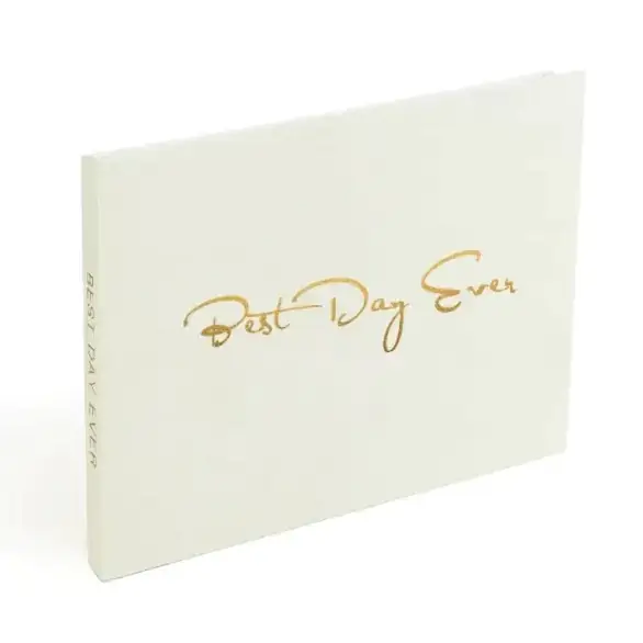 Cream-colored hardcover journal with elegant gold foil lettering that reads ’best day ever’ in a cursive script.