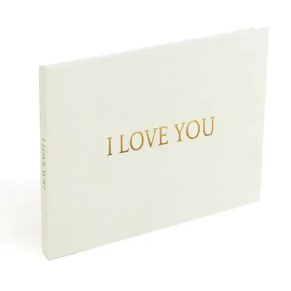 Cream-colored hardcover photo album with gold foil lettering that reads ’i love you’ on the front cover.