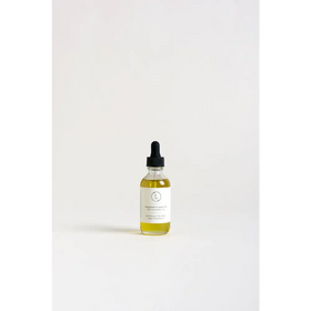 A clear glass bottle with a black dropper cap contains golden-yellow grape seed body oil, labeled ’nourishing & moisturizing’ on its white label.