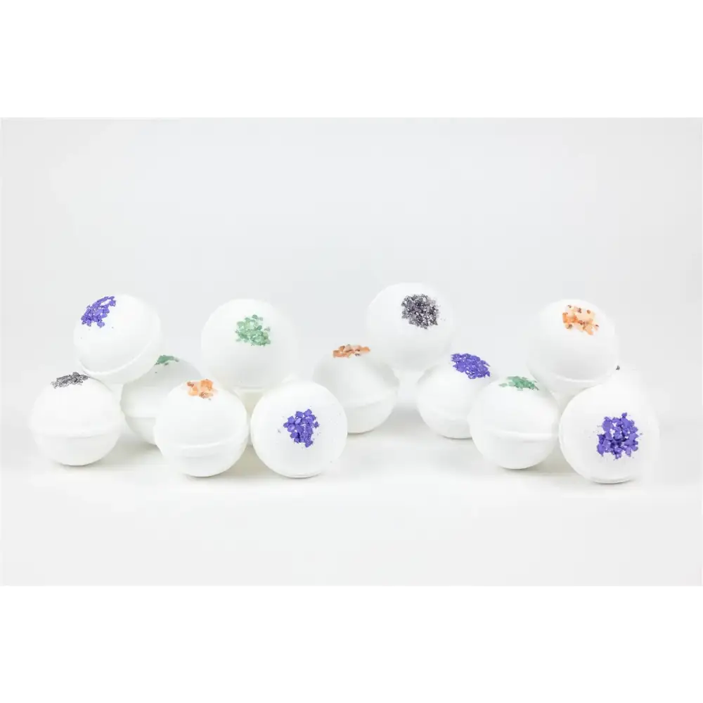 White spherical bath bombs with colorful, glittery floral designs in shades of purple, green, and orange.