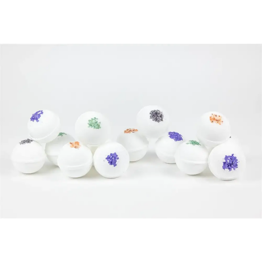 White spherical bath bombs with colorful, glittery floral designs in shades of purple, green, and orange.
