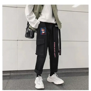 Black cargo pants with multiple pockets, a side belt featuring pink text and chinese characters, and a rectangular patch on the thigh depicting a portrait.