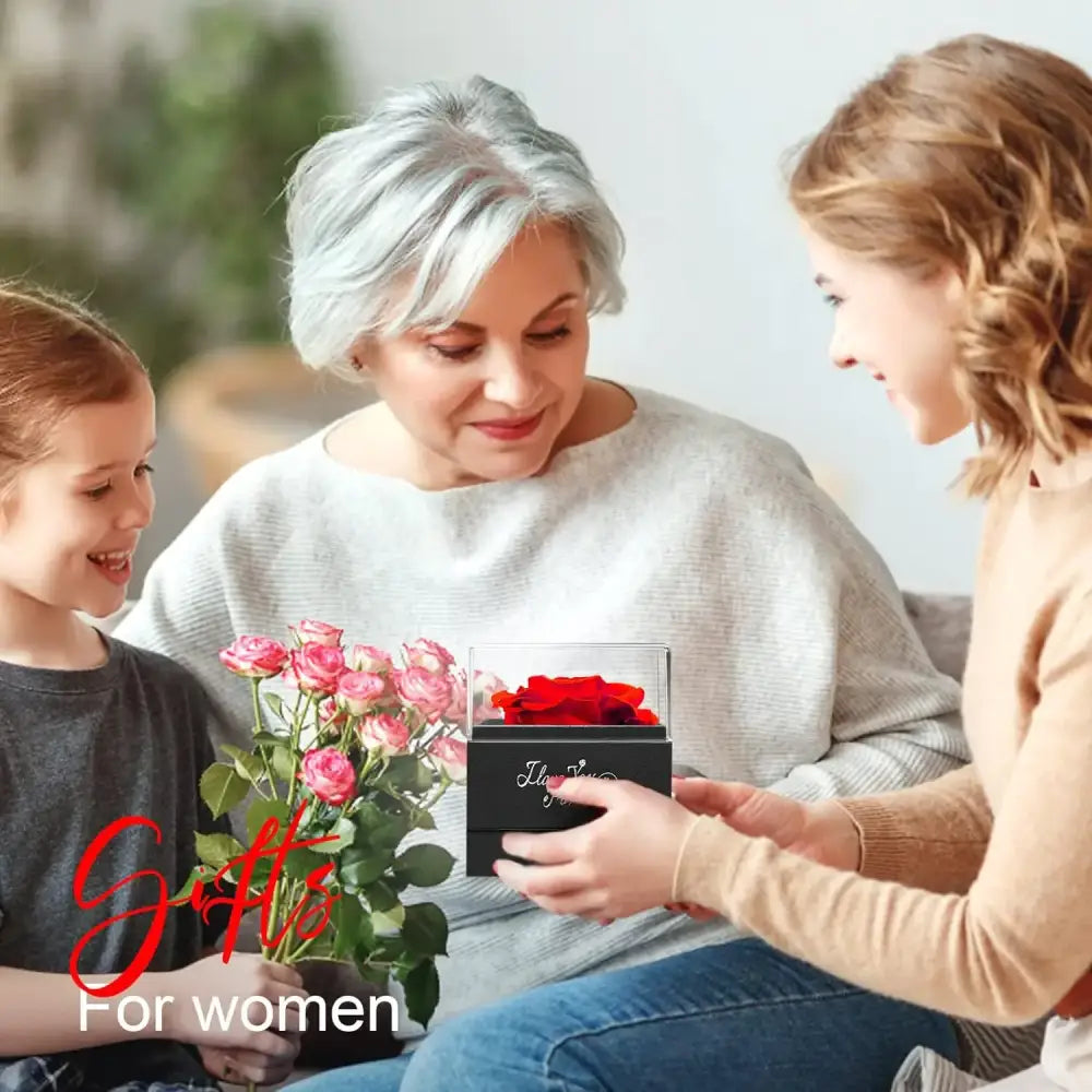A black rectangular box with a clear lid, containing vibrant red preserved roses.