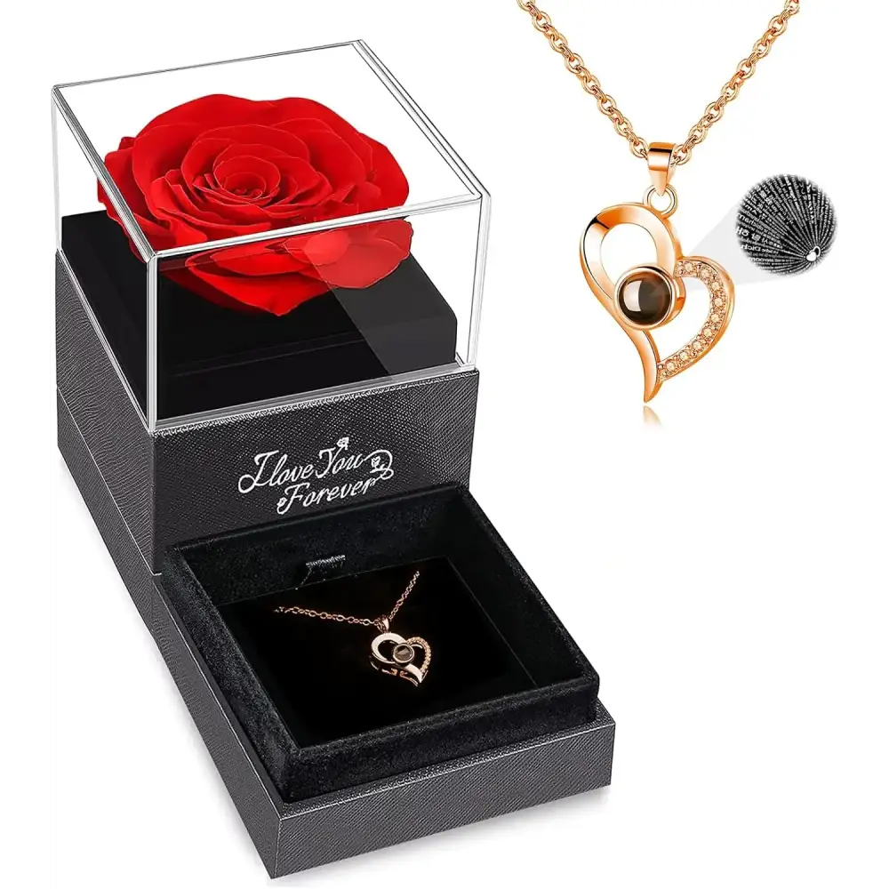 A rose gold heart-shaped pendant necklace with a dark brown gemstone and sparkling rhinestones, displayed in an elegant black gift box alongside a preserved red rose.