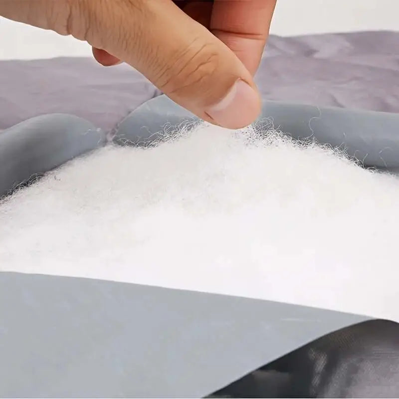 White, fluffy polyester stuffing material being held by a hand.
