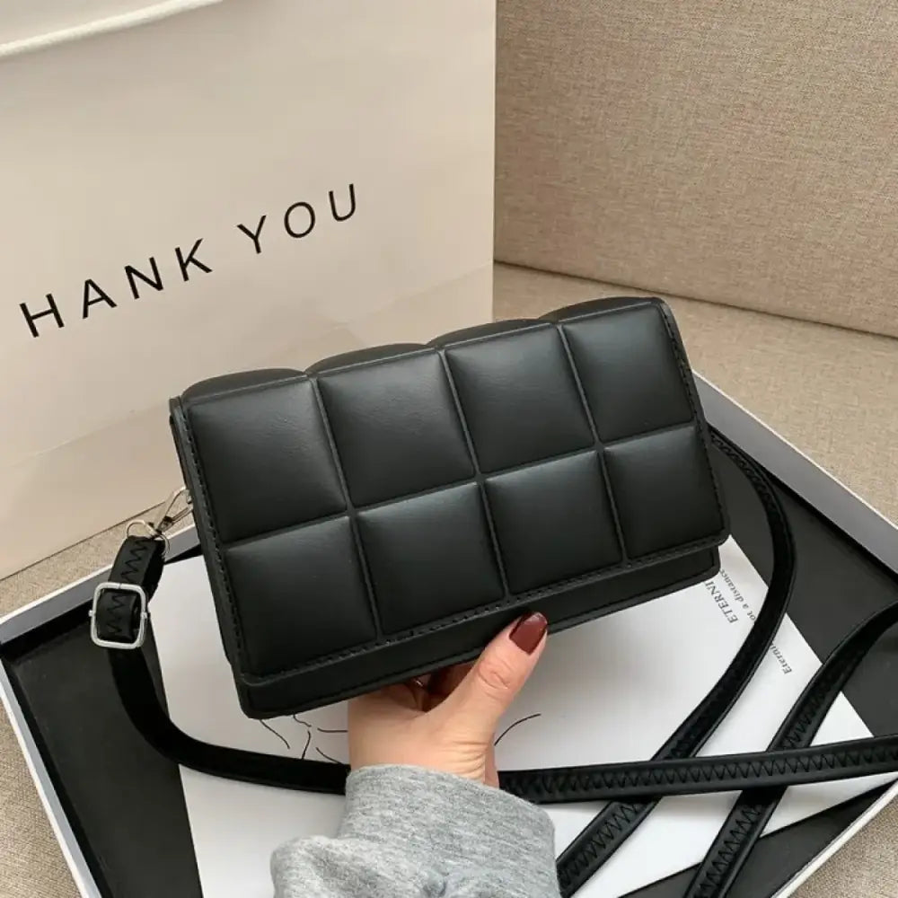 Black quilted crossbody bag with a sleek, structured design and adjustable strap.