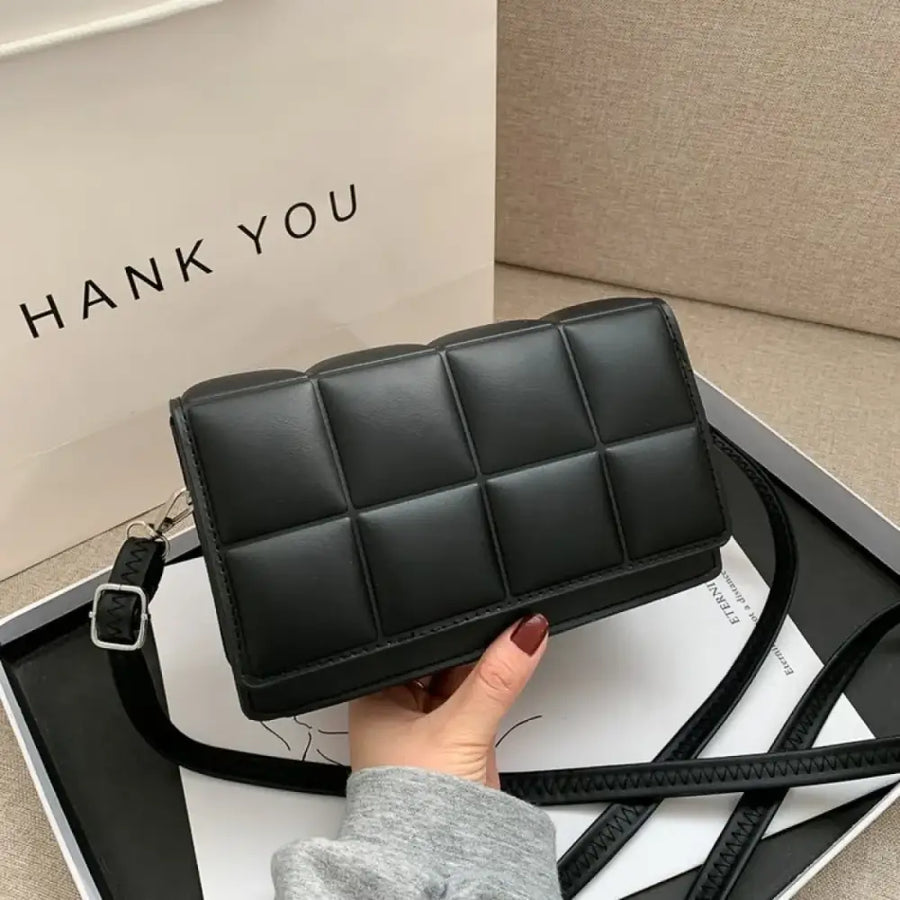 Black quilted crossbody bag with a sleek, structured design and adjustable strap.