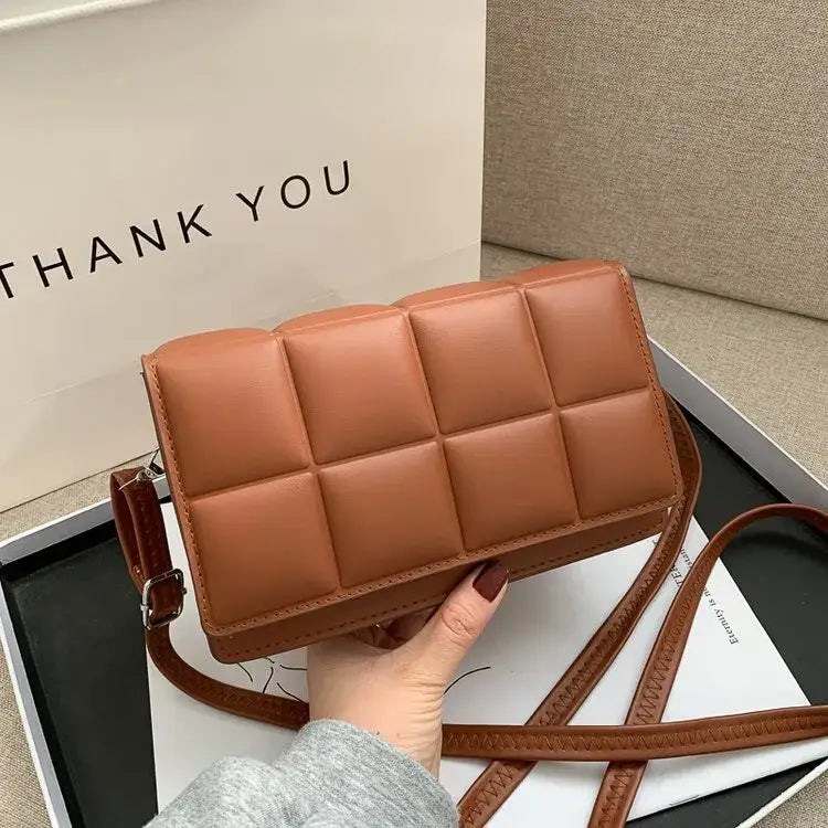 Brown quilted leather crossbody bag with a matching adjustable strap.