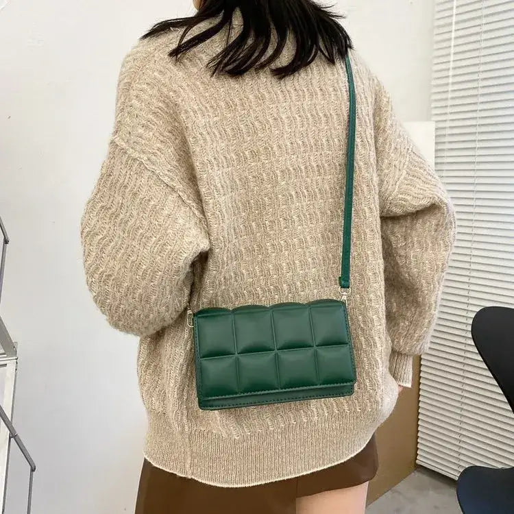 Green quilted crossbody bag with a sleek, structured design and matching strap.