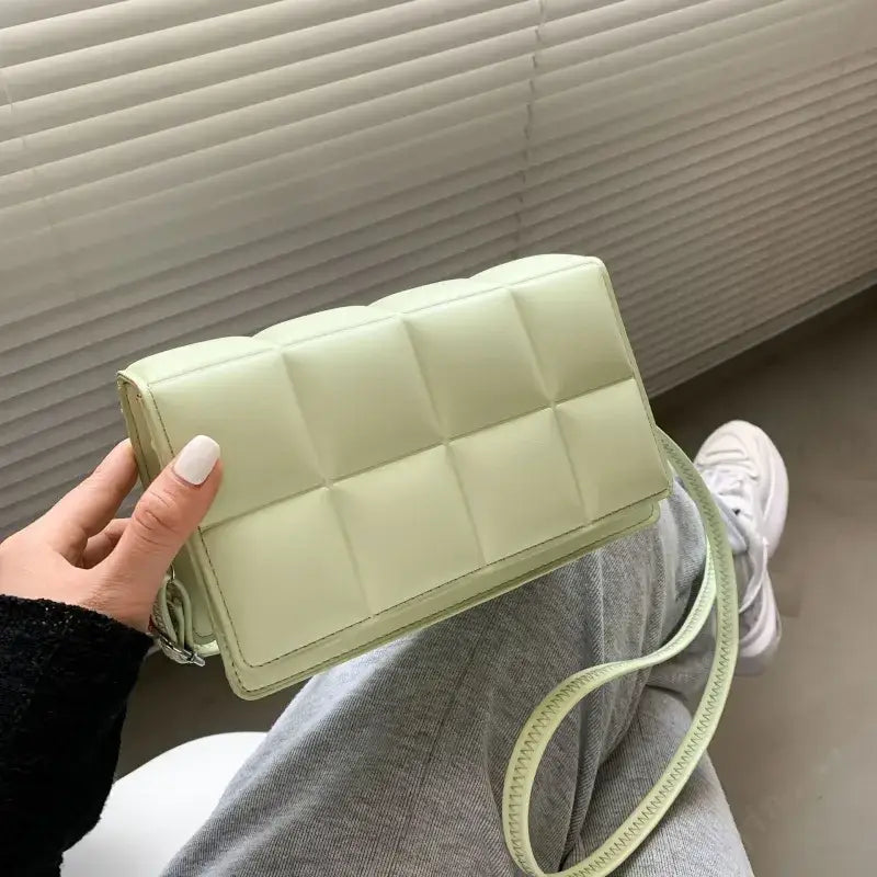 A mint green quilted crossbody bag with a matching adjustable strap.