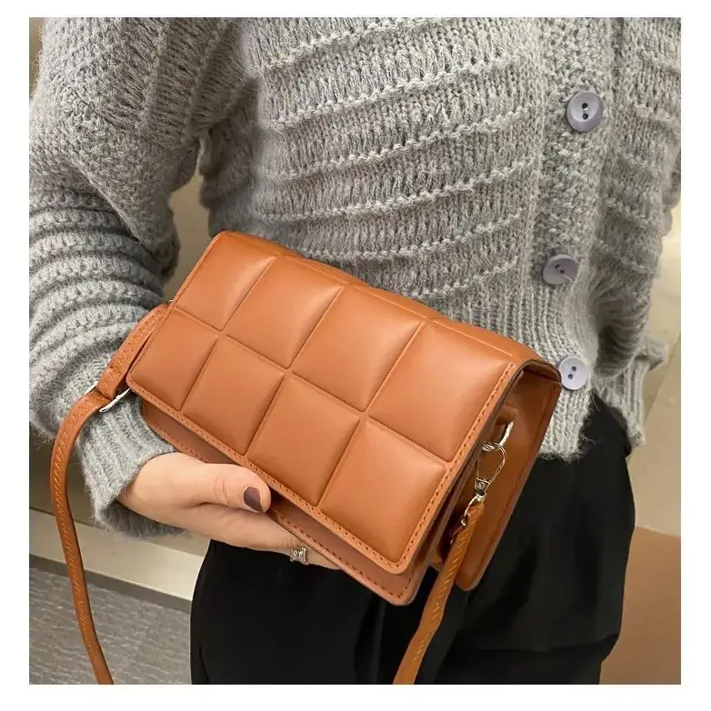 Tan quilted leather crossbody bag with a structured rectangular shape and matching adjustable strap.