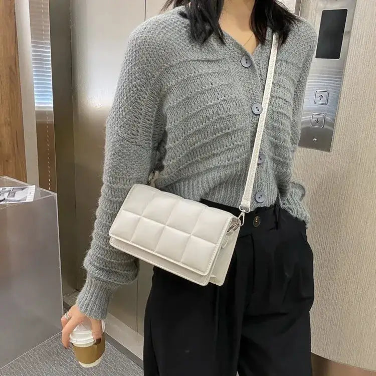 White quilted crossbody bag with a sleek, structured design and silver-toned hardware.