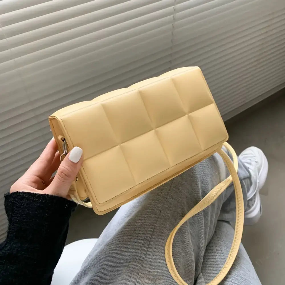 A soft yellow quilted crossbody bag with a matching strap and gold-tone hardware.