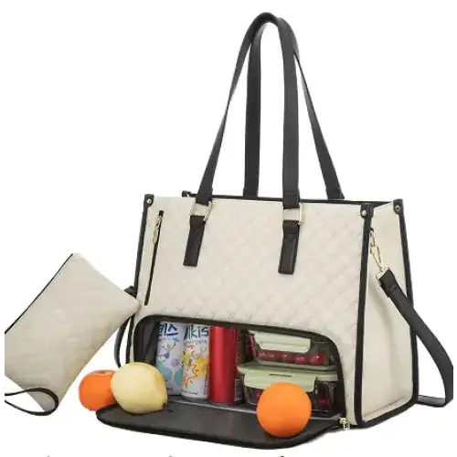 Cream-colored quilted tote bag with black leather straps and trim, featuring a spacious interior filled with food containers and produce.