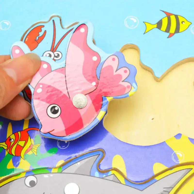 A pink striped wooden fish puzzle piece with a silver button on its belly.