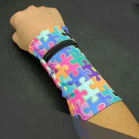 A colorful puzzle-piece patterned wristband with a black zipper.